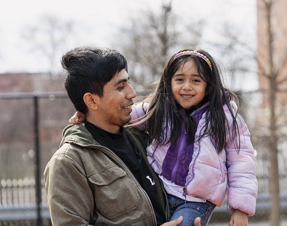 Photo of a father holding his daughter while she is smiling