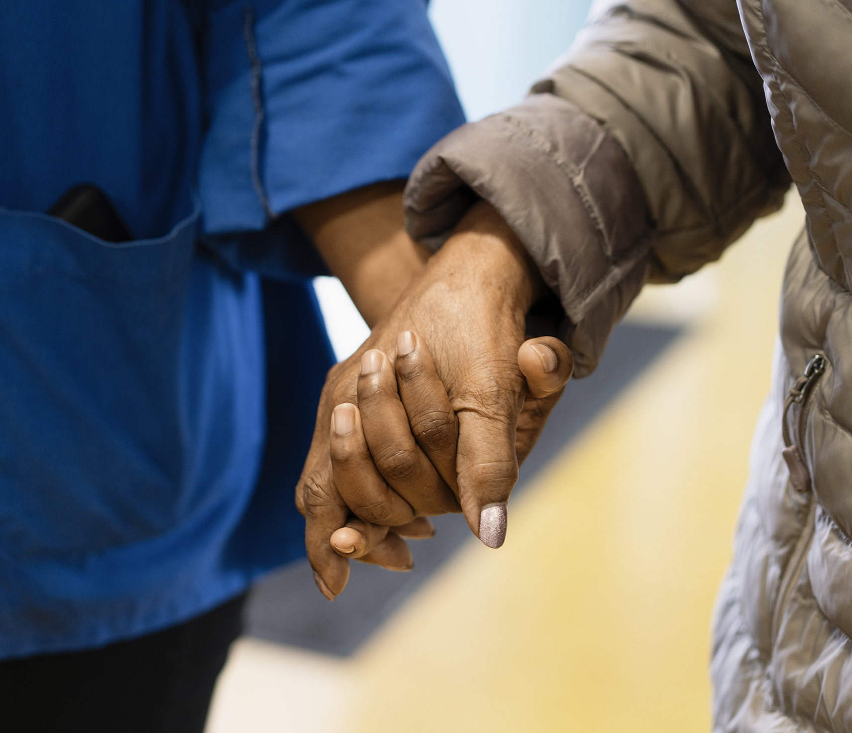 A photo of a senior holding the hand of a worker.
