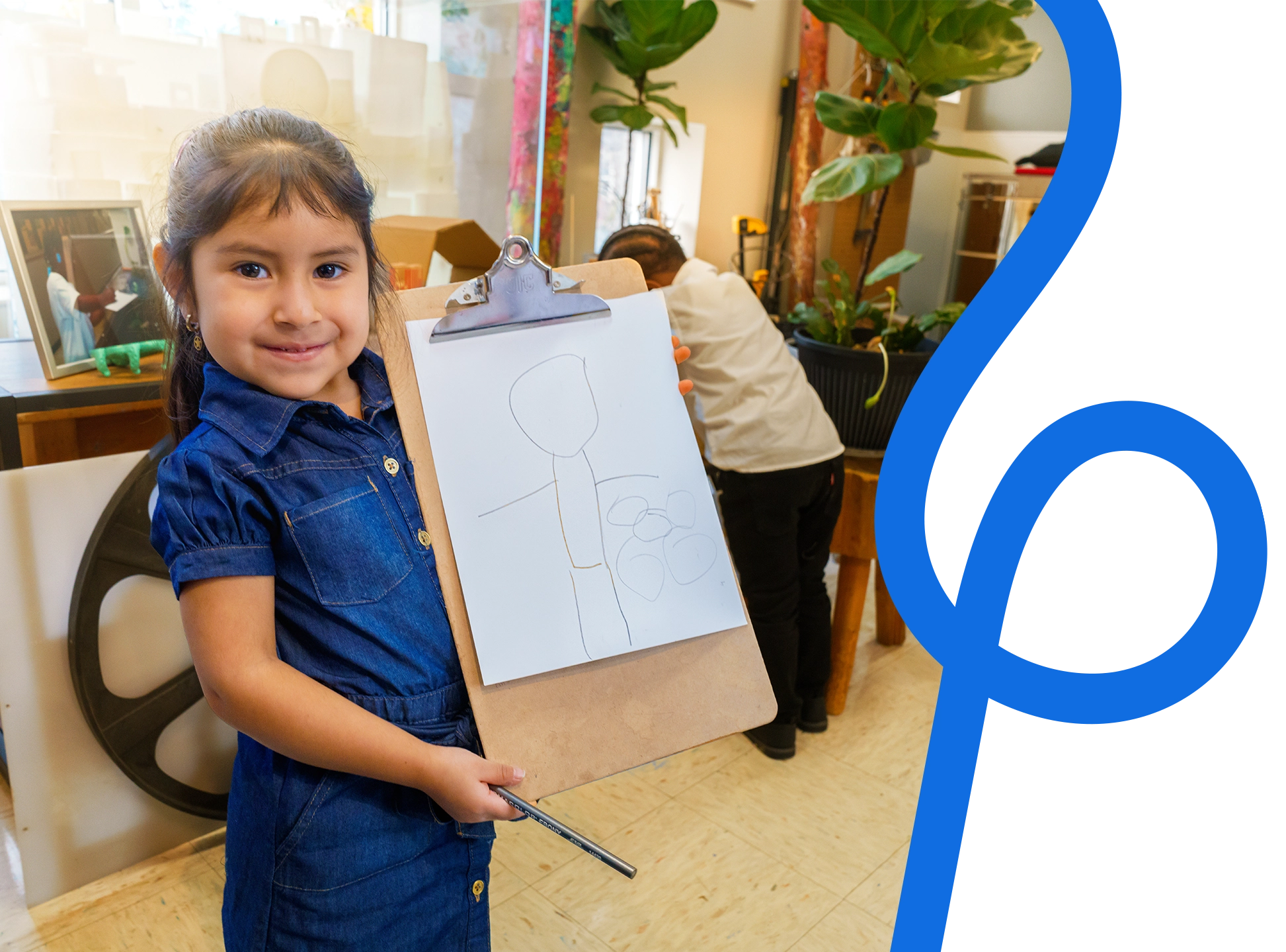 Photo of a little girl holding up her drawing.